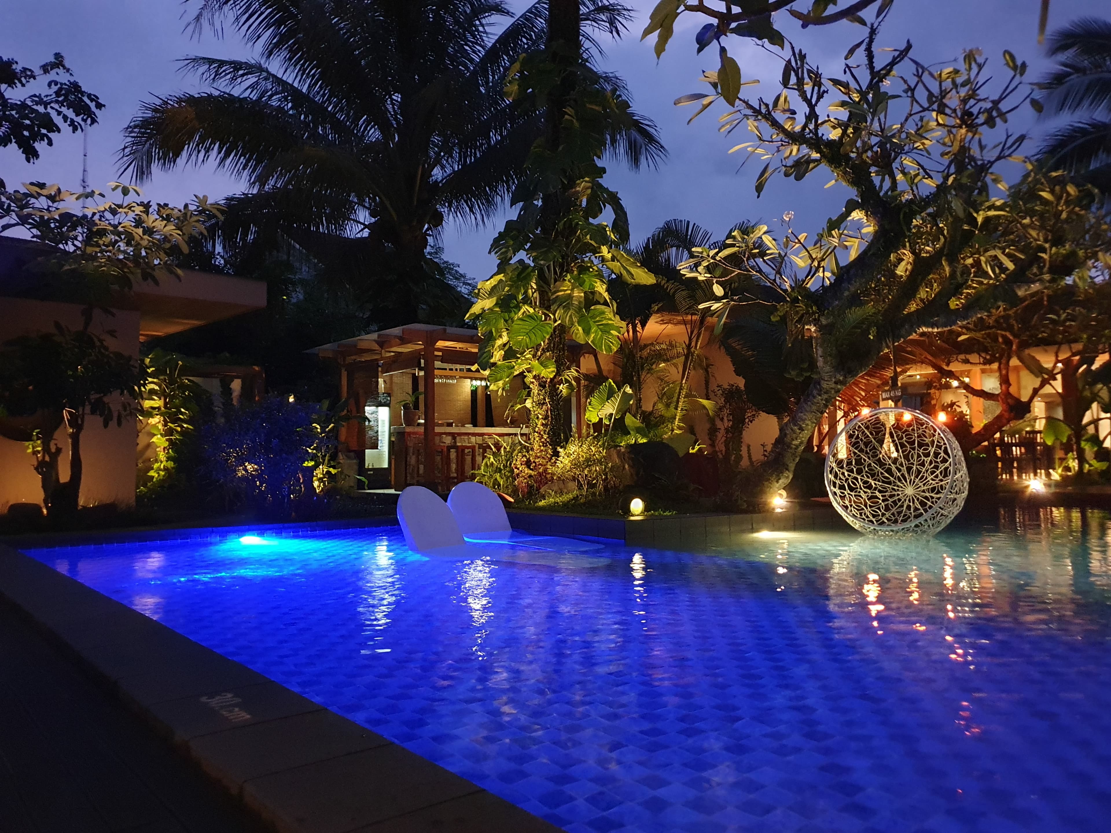 Kolam renang outdoor di malam hari dengan lampu temaram